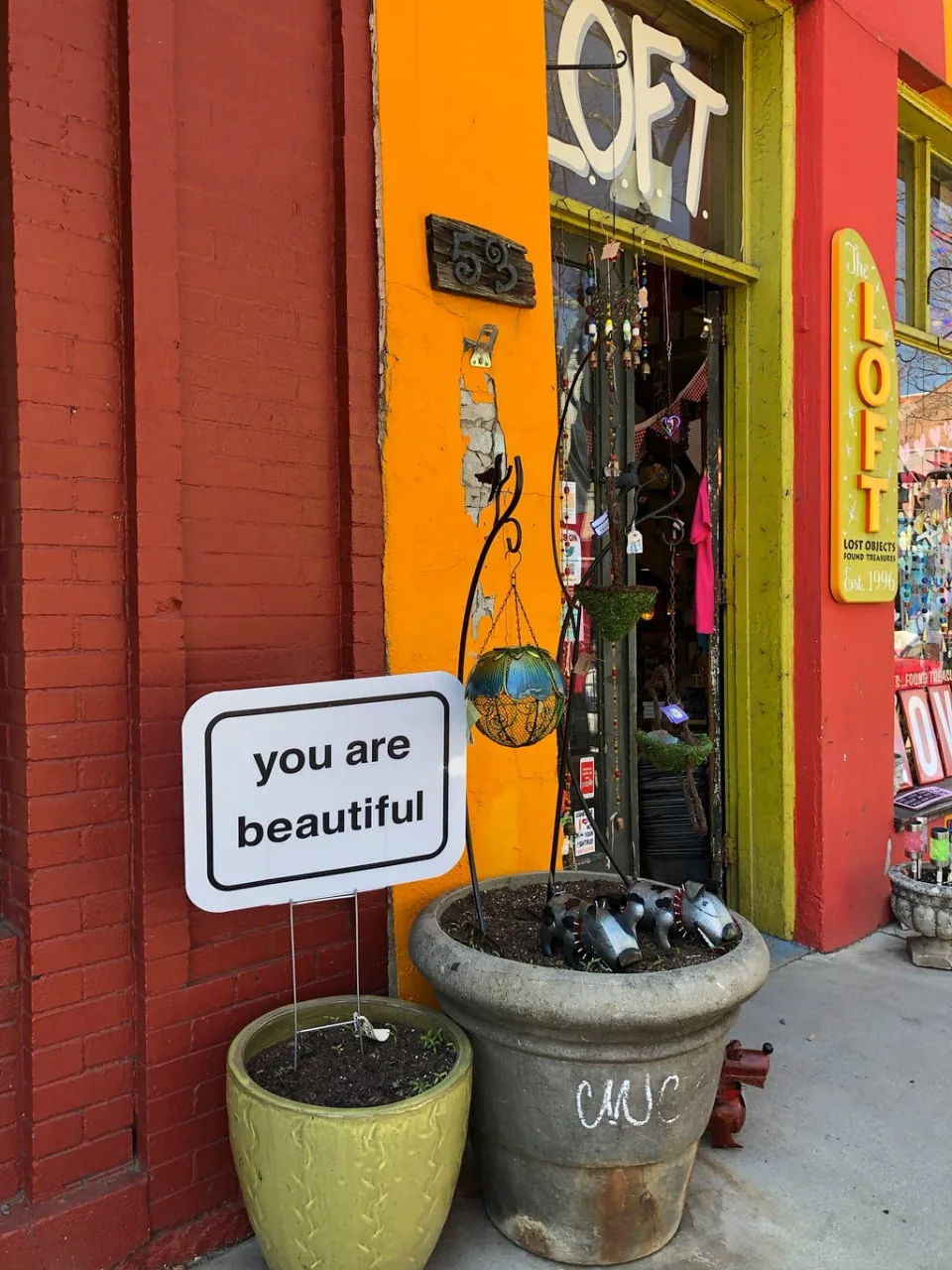 A colorful storefront with a “you are beautiful” sign